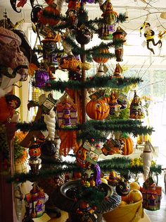 a christmas tree with many ornaments hanging from it's sides in front of a window