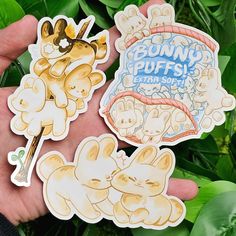 three stickers depicting bunnies, puffs, and other things in their hands