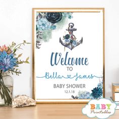 a baby shower sign with an anchor and flowers on the shelf next to it is shown