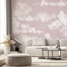 a living room with pink clouds painted on the wall and white furniture in the corner