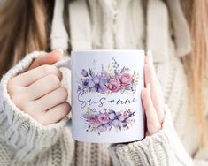 a woman is holding a coffee mug with flowers on it and the words yes santa written in cursive writing