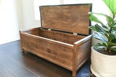 a wooden trunk sitting on top of a hard wood floor next to a potted plant