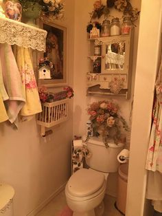 a white toilet sitting in a bathroom next to a shelf filled with towels and flowers