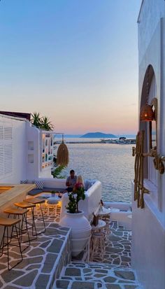 an outdoor seating area overlooking the water at sunset