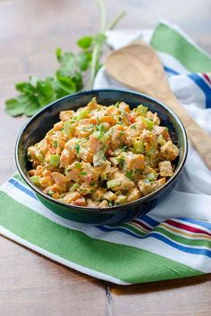 a bowl filled with food sitting on top of a table next to a wooden spoon