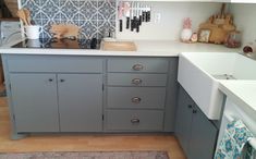 a kitchen with gray cabinets and white counter tops, wooden flooring and utensils hanging on the wall