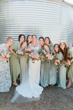 a group of women standing next to each other in front of a metal structure holding bouquets