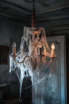 a spider web chandelier hanging from a ceiling in a dark room with candles