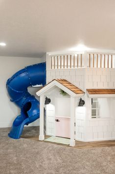 a play house with a slide in the middle and a blue slide on the other side