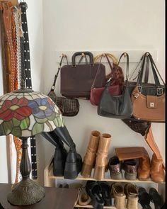 several purses and handbags are hanging on the wall next to a table lamp