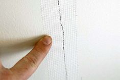 a person's hand is pointing at the edge of a piece of white fabric