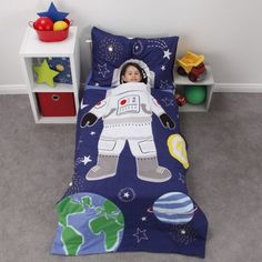 a child's bed with an astronaut print on the comforter and pillowcase