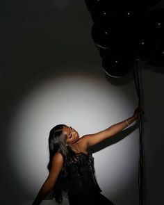 a woman holding onto some black balloons