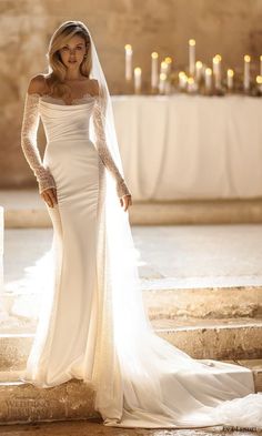 a woman in a wedding dress standing on steps with candles behind her and looking at the camera