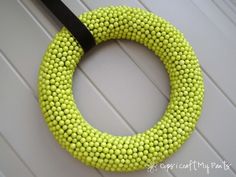 a yellow beaded wreath with a black ribbon hanging on the front door, ready to be decorated