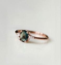 a close up of a ring with a green stone and diamonds on the side,