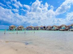 the beach is lined with overhangs and houses on stilts in the water