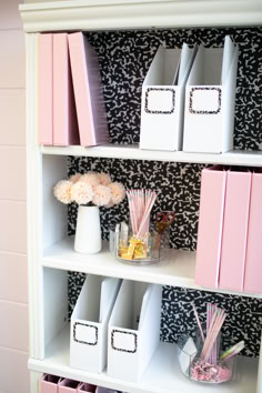 a white book shelf filled with lots of pink and white boxes on top of it