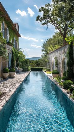 an outdoor swimming pool surrounded by stone walls and greenery, with blue water running through it