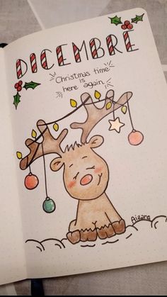 an open notebook with a drawing of a reindeer and christmas lights hanging from it's antlers