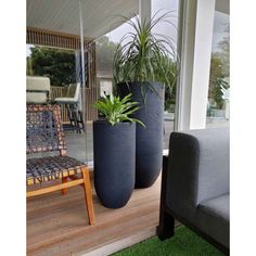 three large planters are sitting on the deck near a couch and chair with grass in front of it