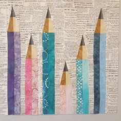 four colored pencils are lined up on top of an old book page with torn pages