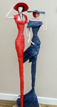 two mannequins dressed in blue and red, one with a hat on her head