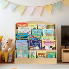 a child's book shelf with books and toys in front of a flat screen tv