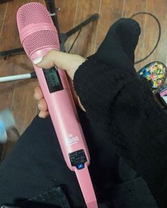 a person holding a pink hair dryer in their left hand and a microphone on the other