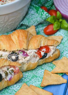 a chicken salad sandwich with tortilla chips on a blue and green table cloth