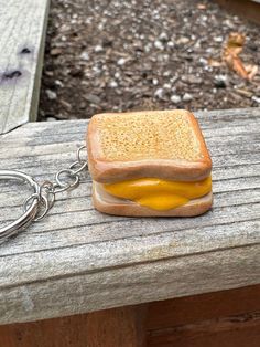 a sandwich shaped keychain sitting on top of a wooden bench