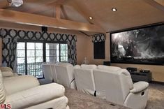 a living room filled with white furniture and a flat screen tv mounted to the wall