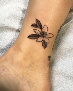 a black and white flower tattoo on the ankle