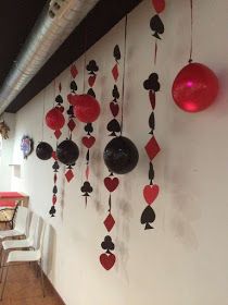 the wall is decorated with red and black playing cards, hearts, and balloons hanging from strings