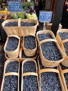 baskets of blueberries are stacked on top of each other in front of produce stand