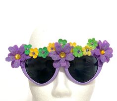 It's Mardi Gras time  Celebrate Mardi Gras with these lightweight childrens sunglasses decorated with glittery purple, green and gold flowers, embellished with rhinestones on purple heart shape sunglasses.  These sunglasses are perfect for parades and parties, in classic Mardi Gras colors - Purple represents Justice, Green represents Faith, and Gold represents Power. I specially treat the glitter so there is little to no shedding.  These sunglasses will get attention when the kiddos are yelling Purple Plastic Party Sunglasses, Purple Glass Sunglasses For Spring, Purple Sunglasses With Uv Protection For Party, Mardi Gras Flowers, Green And Gold Flowers, Sunglasses Decorated, Heart Shape Sunglasses, Mardi Gras Colors, Carnival Parade