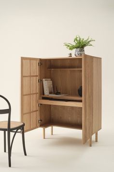 an open cabinet next to a chair with a potted plant on top of it