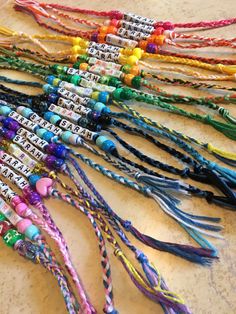 many colorful bracelets are laid out on the table with name tags attached to them