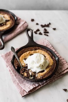 two skillets filled with ice cream on top of pink napkins next to chocolate chips