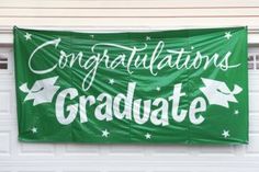 a green banner that says congratulations graduate hanging from the side of a white garage door