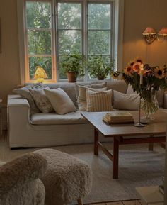 a living room filled with lots of furniture and flowers in a vase on top of a coffee table