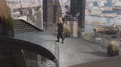 a woman standing on top of a tall building next to a large cityscape