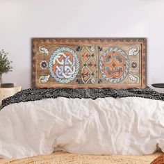 the bed is made up with white linens and an intricately decorated headboard