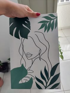 a person holding up a piece of art with leaves on it