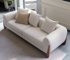 a white couch sitting on top of a rug next to a window