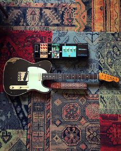 an electric guitar sitting on top of a rug next to a cell phone and other electronic devices