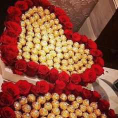 two heart shaped boxes filled with chocolates and roses on top of a table next to each other