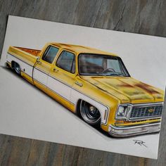 a drawing of a yellow pick up truck on a wooden table next to a piece of paper