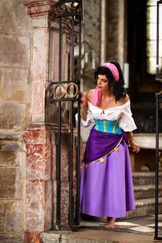 a woman in a purple and blue dress is standing at the entrance to an old building