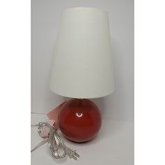 a red lamp sitting on top of a table next to a white light bulb and plug